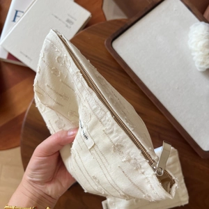 Macro shot of minimalist cream linen makeup bag with zipper and woven texture labels