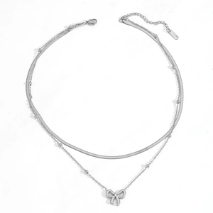 Détail de la chaîne de cheville double argentée avec perles et pendentif nœud