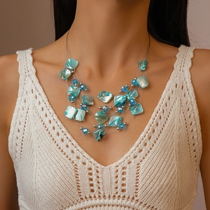 Detail of layered turquoise shell necklace with crystal beads on a model wearing white
