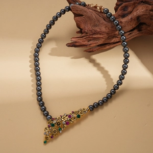 Detail of vintage flower pendant on dark grey pearl necklace over textured wood