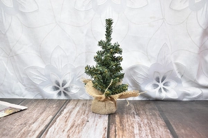 Detail of a mini artificial Christmas tree with green needles and burlap wrapped base