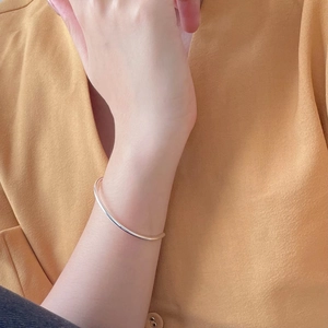 Close-up of minimalist polished silver geometric slim bangle worn on wrist