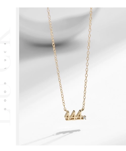 Close-up of golden number 444 pendant necklace with a small sparkling diamond accent