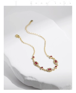 Detailed view of a gold-plated bracelet with red gemstones and sparkling crystal accents