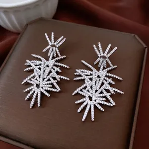 Elegant silver starburst drop earrings with sparkling cubic zirconia on a velvet display