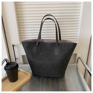Close-up of black woven tote bag texture with leather handles and beige lining detail