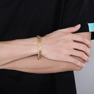 Détail d'un bracelet gourmette en acier inoxydable doré avec plaque ID sur un poignet masculin
