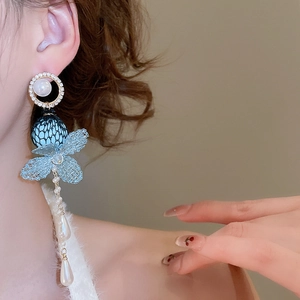 Macro detail of long tassel earrings with blue lace flowers and white drop pearls