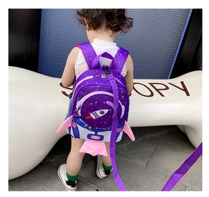 Close-up of a purple rocket-shaped toddler backpack with safety leash in an outdoor setting