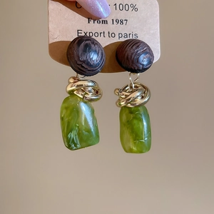 Détail de boucles d'oreilles vintage avec pendentifs en résine verte et nœuds dorés