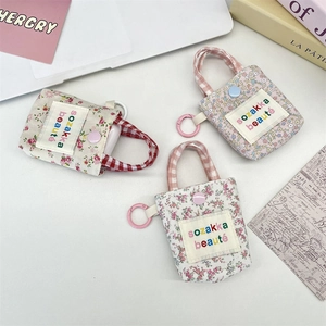 Close-up of three floral and checkered mini fabric pouches with hooks for AirPods