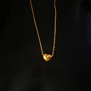 Minimalist 3D heart pendant necklace in 18K gold plated stainless steel on black background