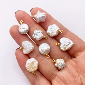 Close-up of heart and star shaped freshwater pearl pendants with gold bails held in hand
