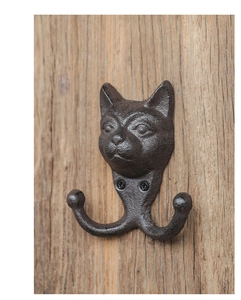 Detail eines Vintage-Wandhakens aus Gusseisen mit Katzenkopf auf einer Holzoberfläche