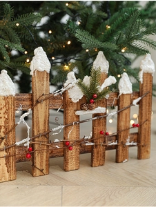Detail of wooden Christmas fence with faux snow, red berries and pine needles