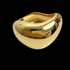Makro-Detail eines glänzenden goldenen Wellenarmreifs mit spiegelnder Metalloberfläche