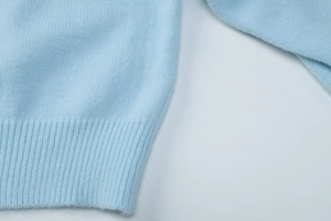Detailed view of light blue knit cardigan showing ribbed cuffs and soft wool texture
