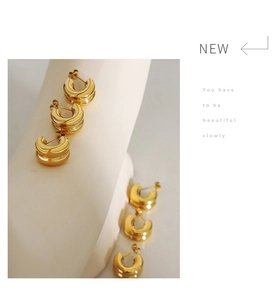 Detailed view of chunky gold double-layered C-shaped hoop earrings with a polished finish