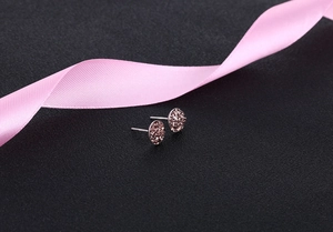 Detailed view of rose gold round crystal stud earrings on a pink silk ribbon backdrop
