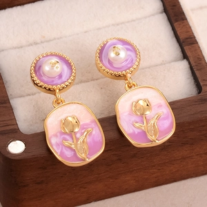 Macro shot of purple enamel tulip earrings with pearl accents in a wooden jewelry box