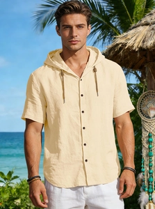Close-up of beige linen hooded shirt with drawstring and buttons in beach setting