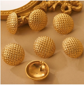 Detailed macro view of gold-plated quilted rhombus pattern stud earrings and backings