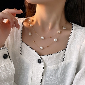 Detailaufnahme einer zweilagigen Goldkette mit weißen Barockperlen am Model
