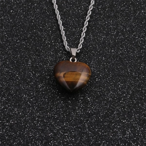 Detail of tiger eye heart pendant with silver twist chain on black sparkle background
