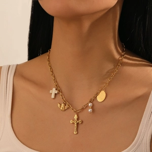 Detail of vintage gold-plated stainless steel necklace with cross, angel, and pearl charms