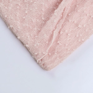 Détail de robe rose en tricot ajouré montrant la texture délicate et le motif à pois