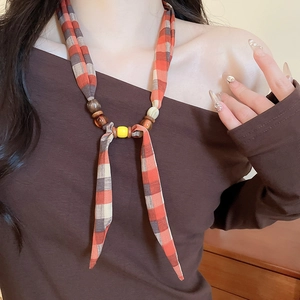 Detail of fabric and bead necklace featuring plaid patterns and wooden accents