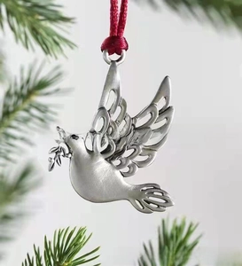 Detailed view of silver metal peace dove pendant with red ribbon on green pine branch