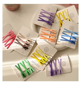 Flat lay of colorful matte metal hair clips on cards with wave design and trendy pastel colors