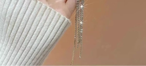 Macro shot of silver tassel earrings with sparkling rhinestones on a warm brown background
