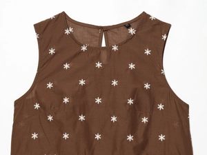 Detail eines dunkelbraunen Tanktops mit weißer Schneeflockenstickerei und XS-Etikett