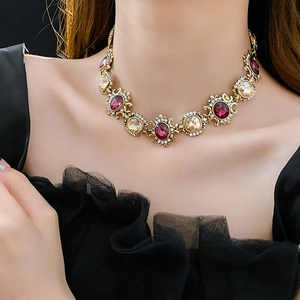 Close-up of vintage gold necklace with red and amber gems worn by model on neck