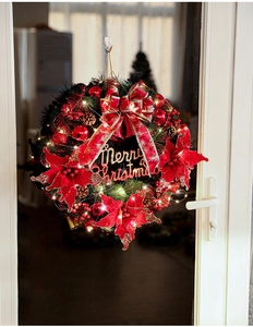 Detail of lit Christmas wreath with pine cones and red bows on a wooden door