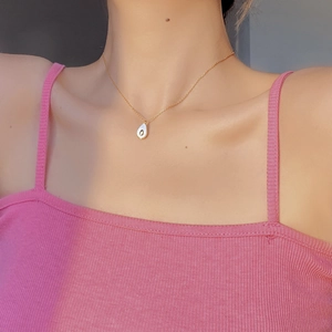 Close-up of elegant gold necklace with white teardrop pendant worn on person