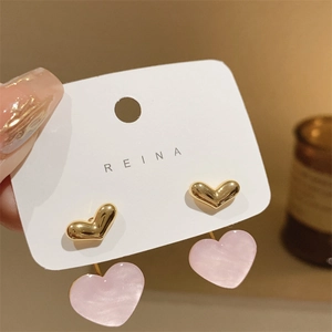Detail of pink heart earrings with gold finish on jewelry card being held by hand