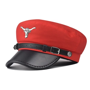 Détail de la casquette militaire rouge avec visière en cuir noir et emblème tête de taureau