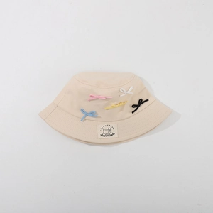 Detailed top view of beige sun hat featuring colorful knitted bows and brand patch