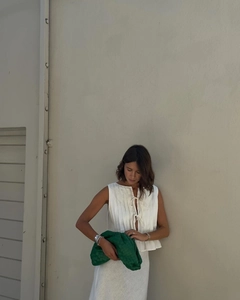 Detail of pleated sleeveless top with front tie and green woven leather handbag