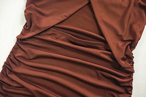 Macro detail of rust red pleated fabric showing precise stitching and ruched texture
