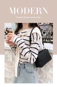 Detail of a black quilted crossbody bag with gold hardware and geometric chain design