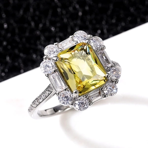 Macro shot of rectangular yellow zircon ring with silver-plated prong setting and diamonds