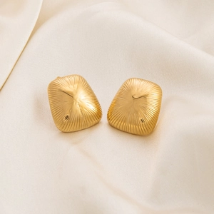 Macro shot of gold-plated earrings with radial knit texture on elegant beige silk fabric