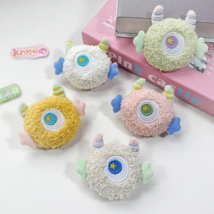 Detailed view of colorful plush monster pins with soft faux fur and star-eye embroidery