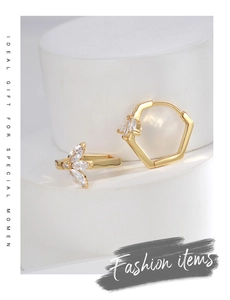 Detail of gold-plated leaf zircon earrings on white steps featuring geometric design