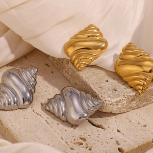 Detailed view of two pairs of conch shell earrings in polished gold and silver finishes