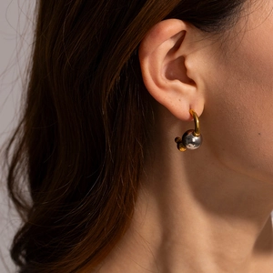 Vue détaillée de boucles d'oreilles boules bicolores or et argent portées par un modèle